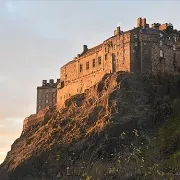 Edinburgh Castle glowing in the golden light atop Castle Rock during sunset.