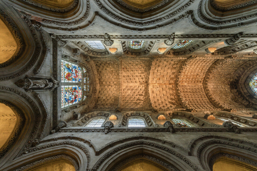 Ornate vaulted ceiling of Rosslyn Chapel featuring stone carvings and stained glass windows.