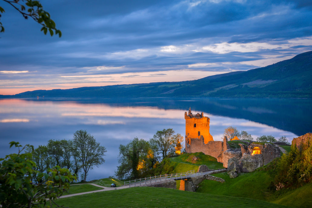 Illuminated castle ruins on the shore of Loch Ness at sunset in the Scottish Highlands